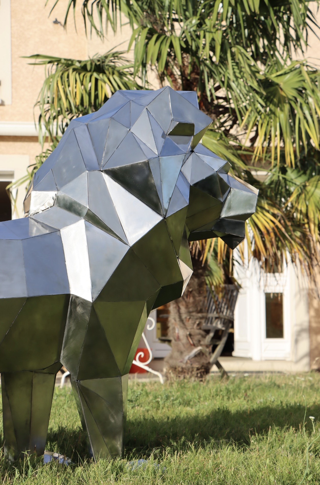 Lion en inox sous un palmier